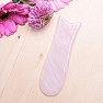 Gua sha on a face made of rose quartz in the shape of a fish